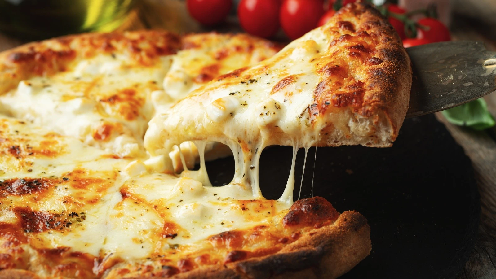 Triple cheese pizza with stretchy melted mozzarella being pulled at Pizzanapoli Lloydminster